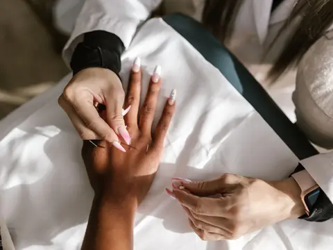Practitioner working at the back of a patient's hand on a white treatment table